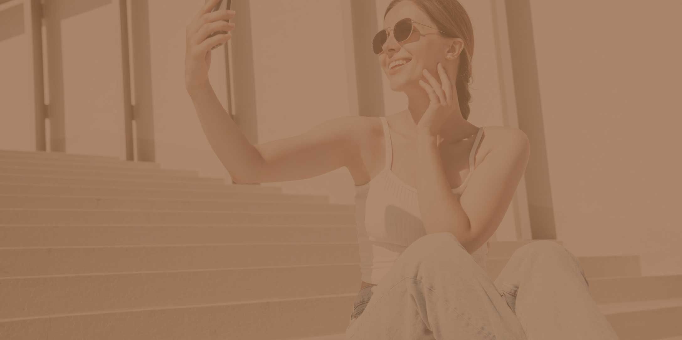 woman with sunglasses looking at her phone and smiling